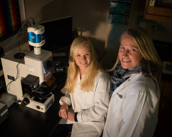 Image of faculty and student in the microscopy lab while smiling at the camera