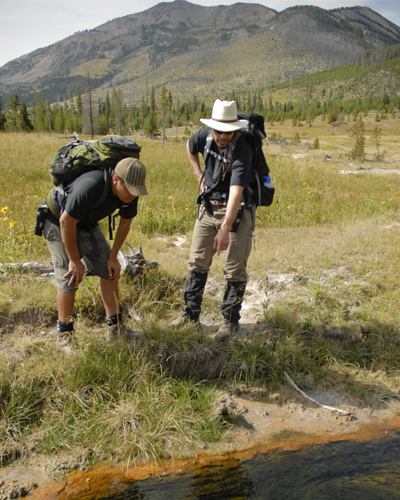 Image of faculty member and graduate student looking at a thermal spring in Yellowstone.