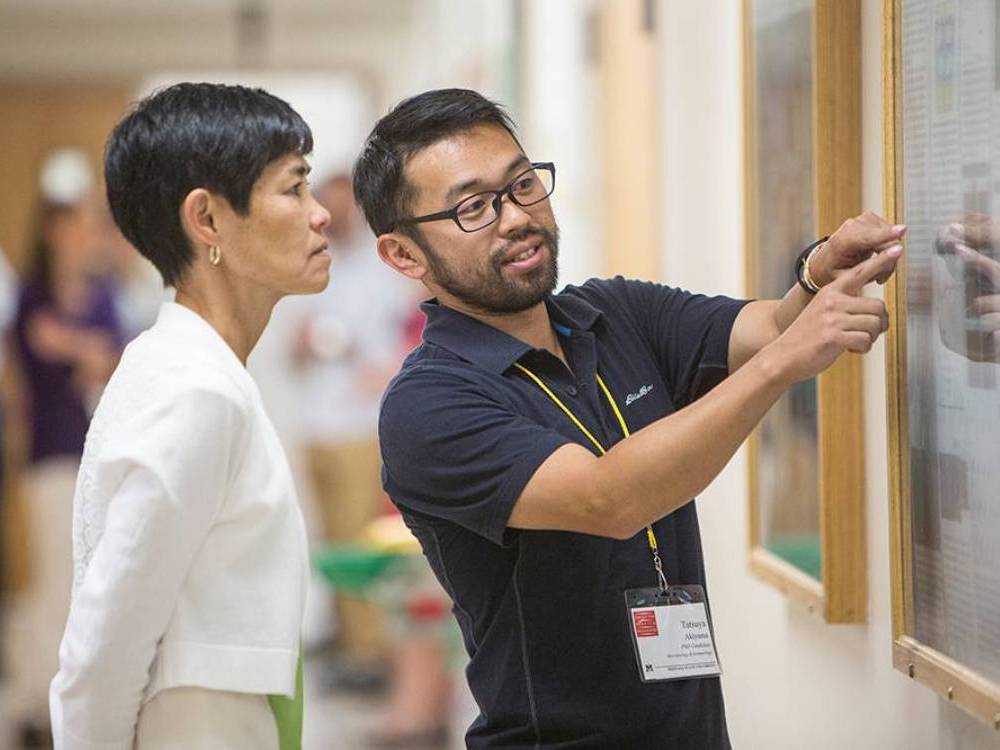 Image of graduate student presenting poster on facutly member