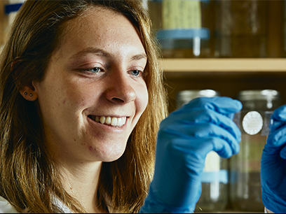 Image of undergraduate smiling at microscopy slide.